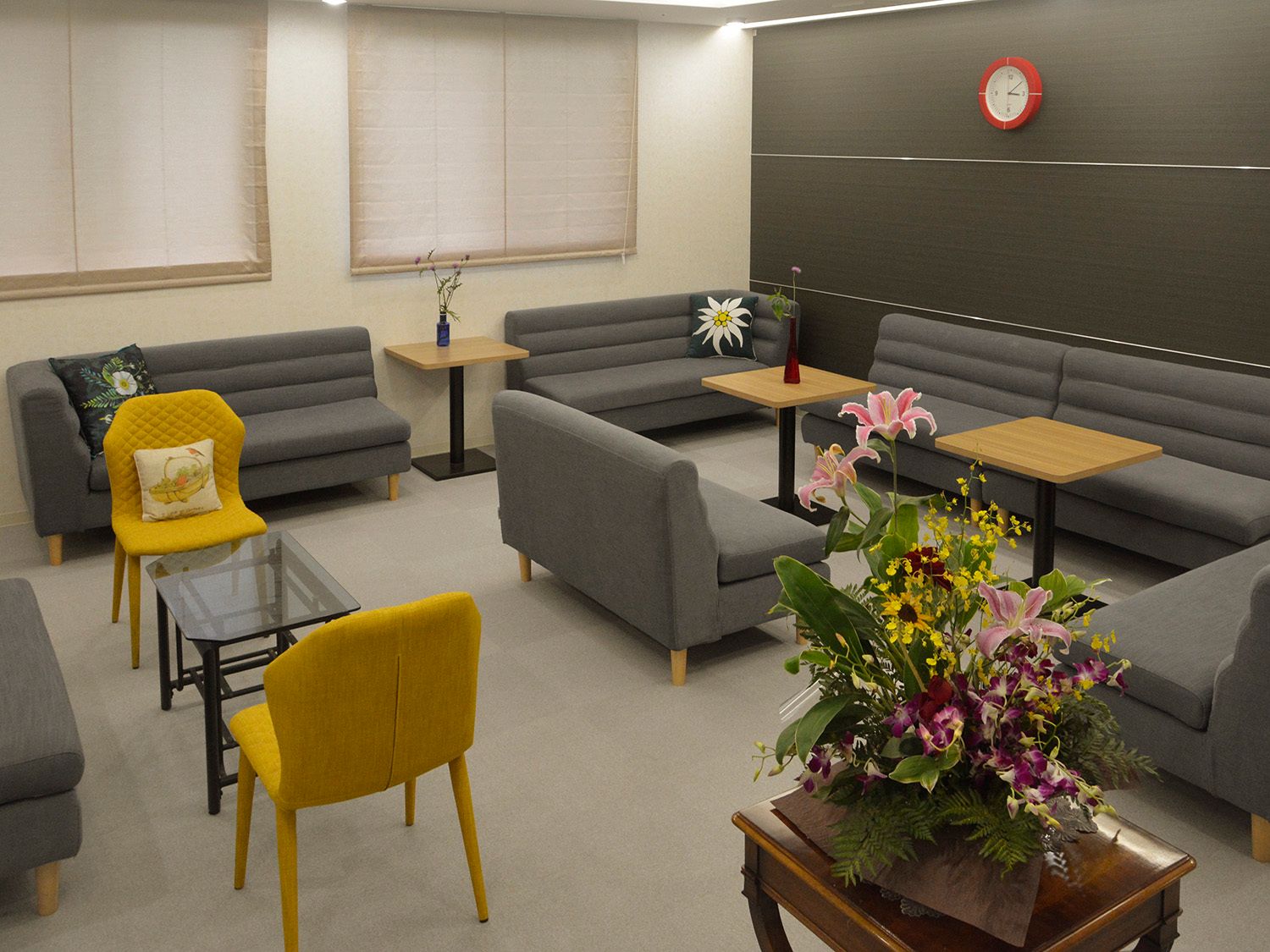 たくさんの酒のボトルが並べられた棚が付いたカウンター。オレンジの椅子が4脚並べられ、テーブルの上には何もない。