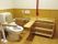 背もたれや手すりが付いた便座が設置されたトイレ。壁には真っ赤な手すりが付き、トイレ前方にもバーが設置できる。