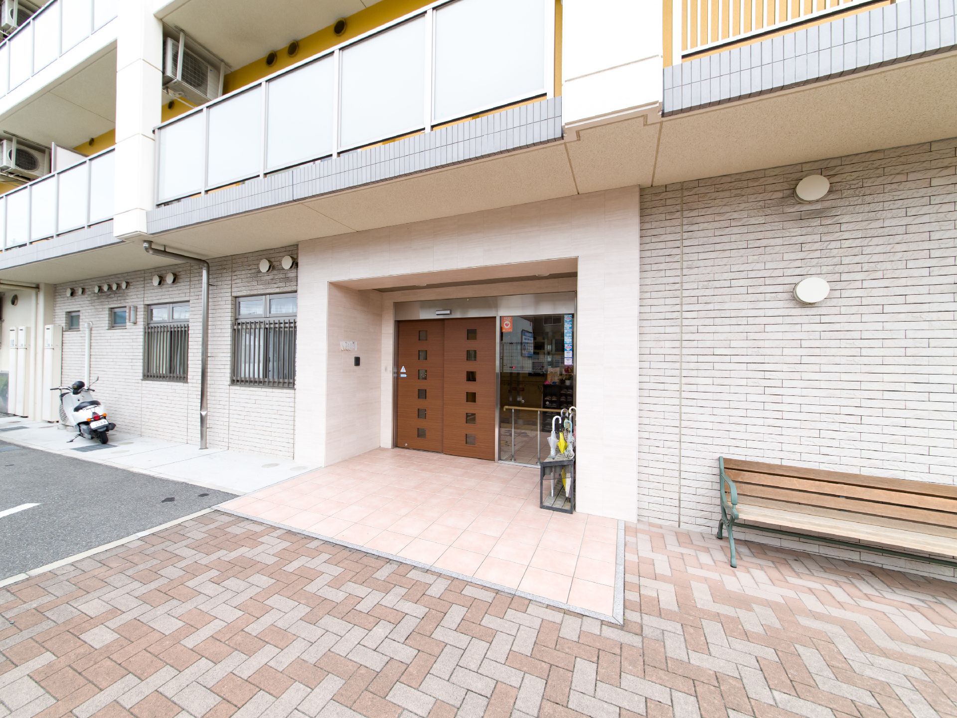 施設の入り口周辺には、傘立てやベンチが置かれている。木が使われた自動ドアをくぐると、すぐに手すりがある。