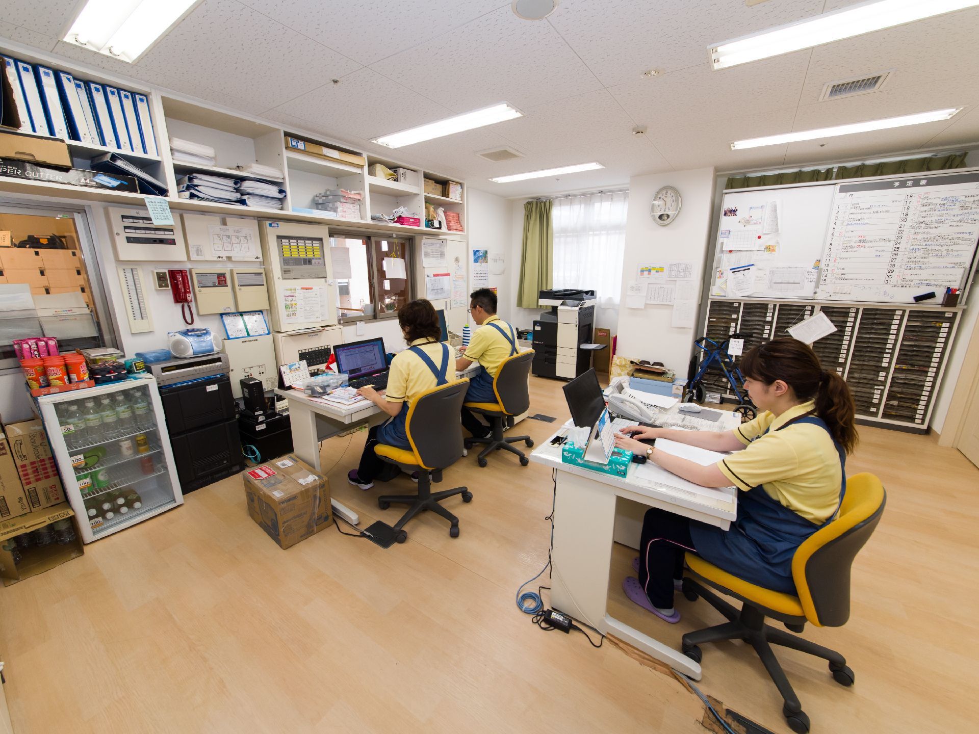 スタッフルームには、デスクが3台あり、それぞれパソコンで仕事をすることが可能。部屋の中には、飲み物を入れるショーケース型の冷蔵庫がある。