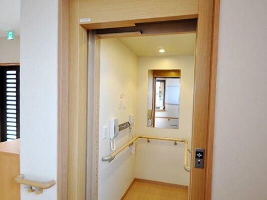 手すりが設置されたエレベーター。庫内には電話や手すり、鏡が付いている。左側には玄関のドアが付いている。