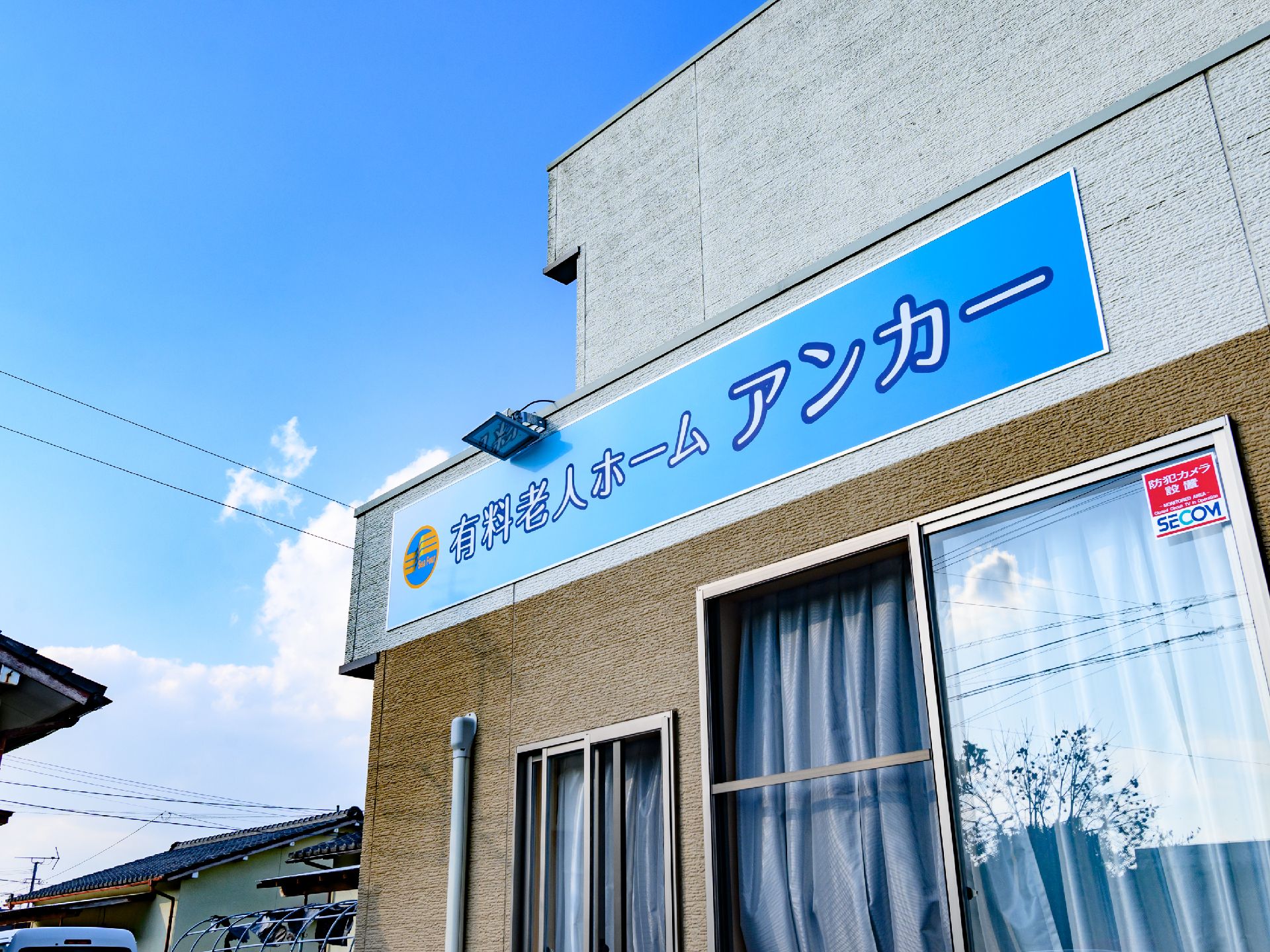 ２階建てで、青色の看板が設置された介護施設の外観