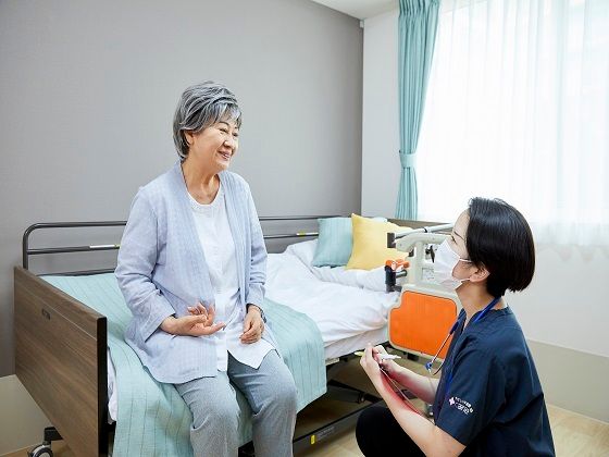高齢者と一緒にカルテのようなものを眺めている施設内スタッフとの2ショット
