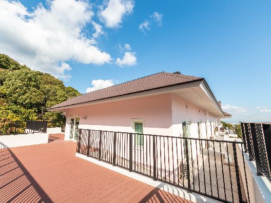 広いテラスで思い思いに過ごす高齢者たち。新聞を読んだり、景色を見たり、話したり、花に水をやっている。