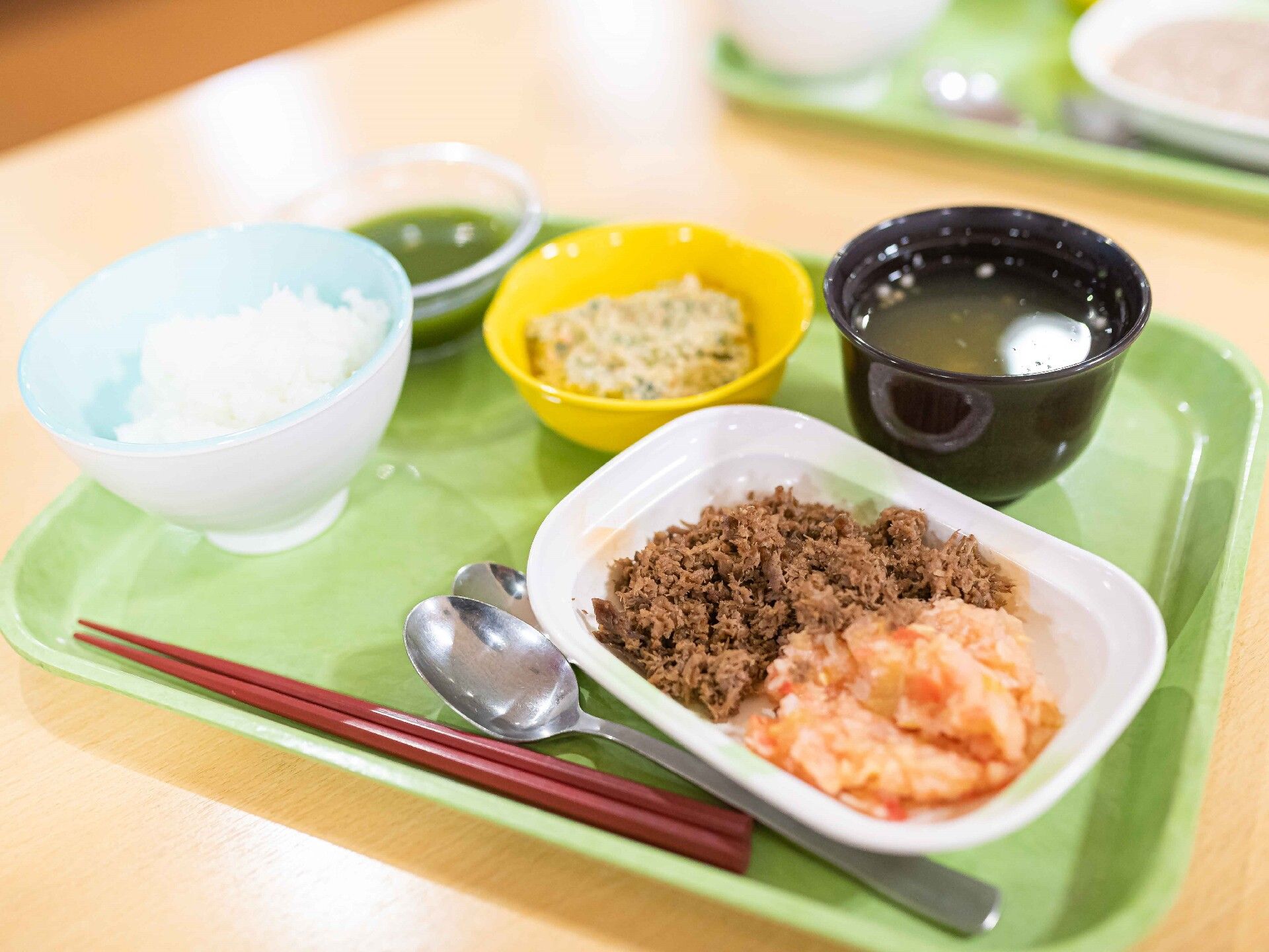 箸やスプーンが置かれているグリーンのトレーの上には刻み食が並んでいる。通常食に近い色合い。
