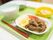 グリーンのトレーの上には牛肉の料理と小鉢が二つ、白いご飯が並び、箸やスプーンが置かれている。