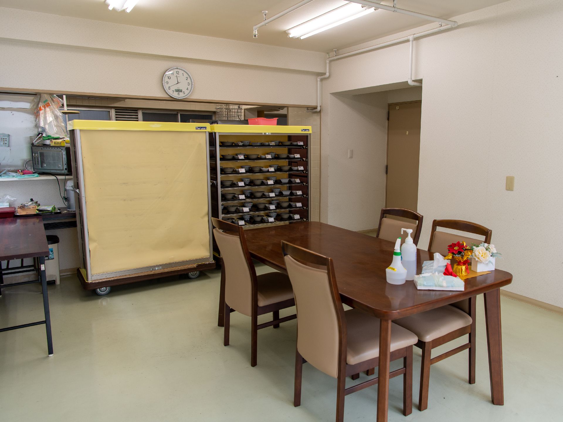 白い壁の部屋の中央に置かれた木製の机と４脚の椅子