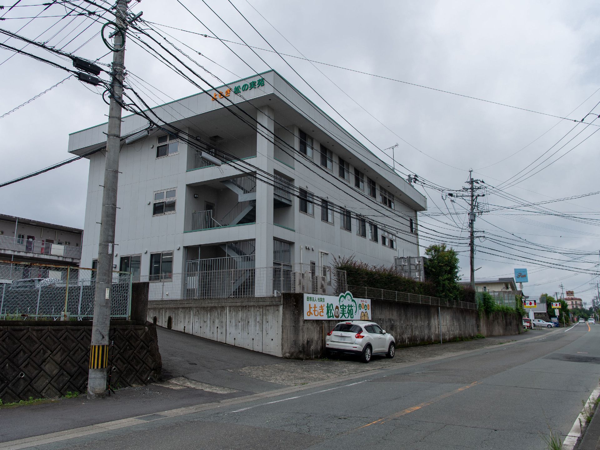 道路より高度が高い場所に立地している３階建ての白い建物