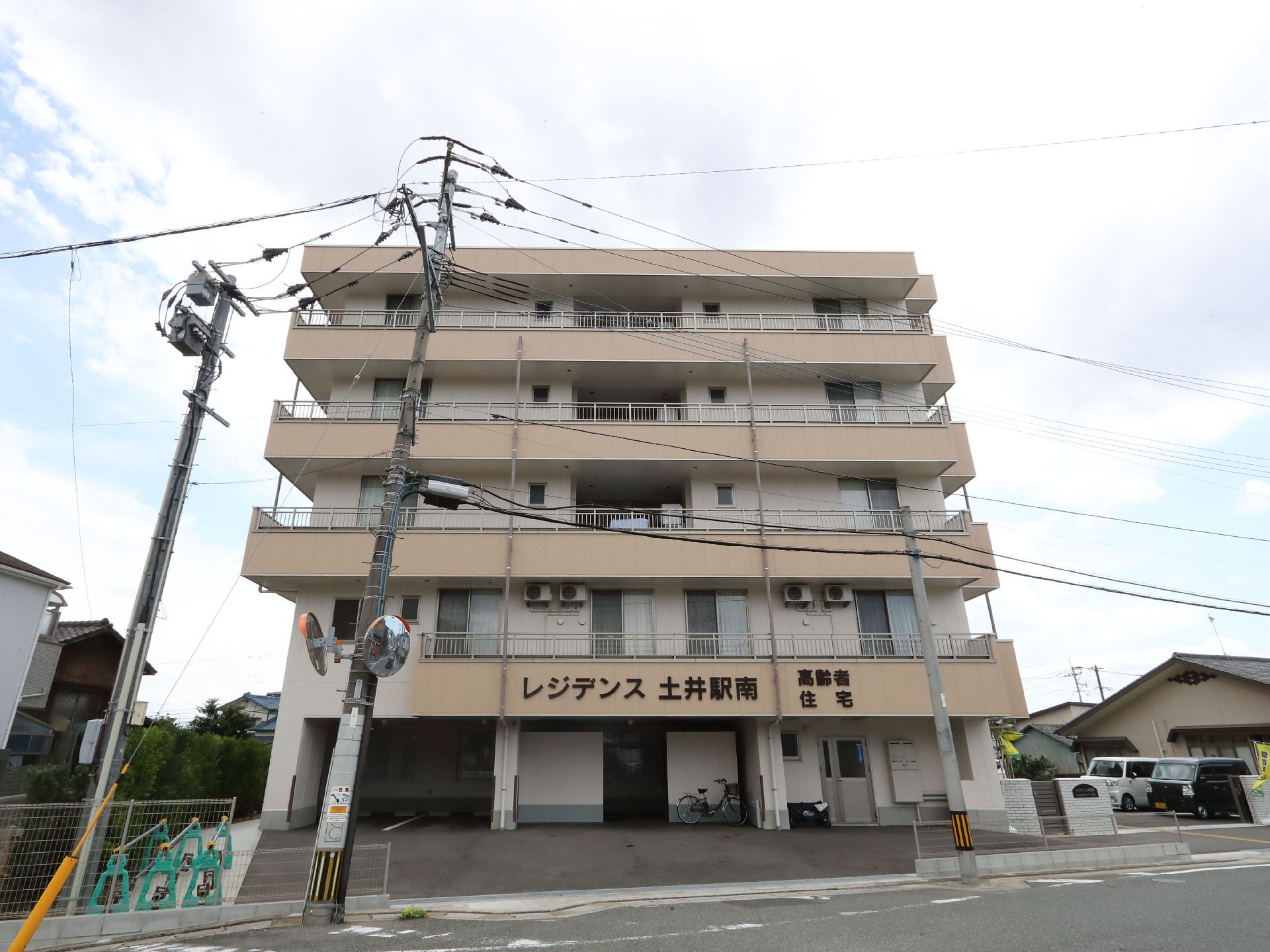 道路沿いに立地している白とベージュの外観で５階建ての建物