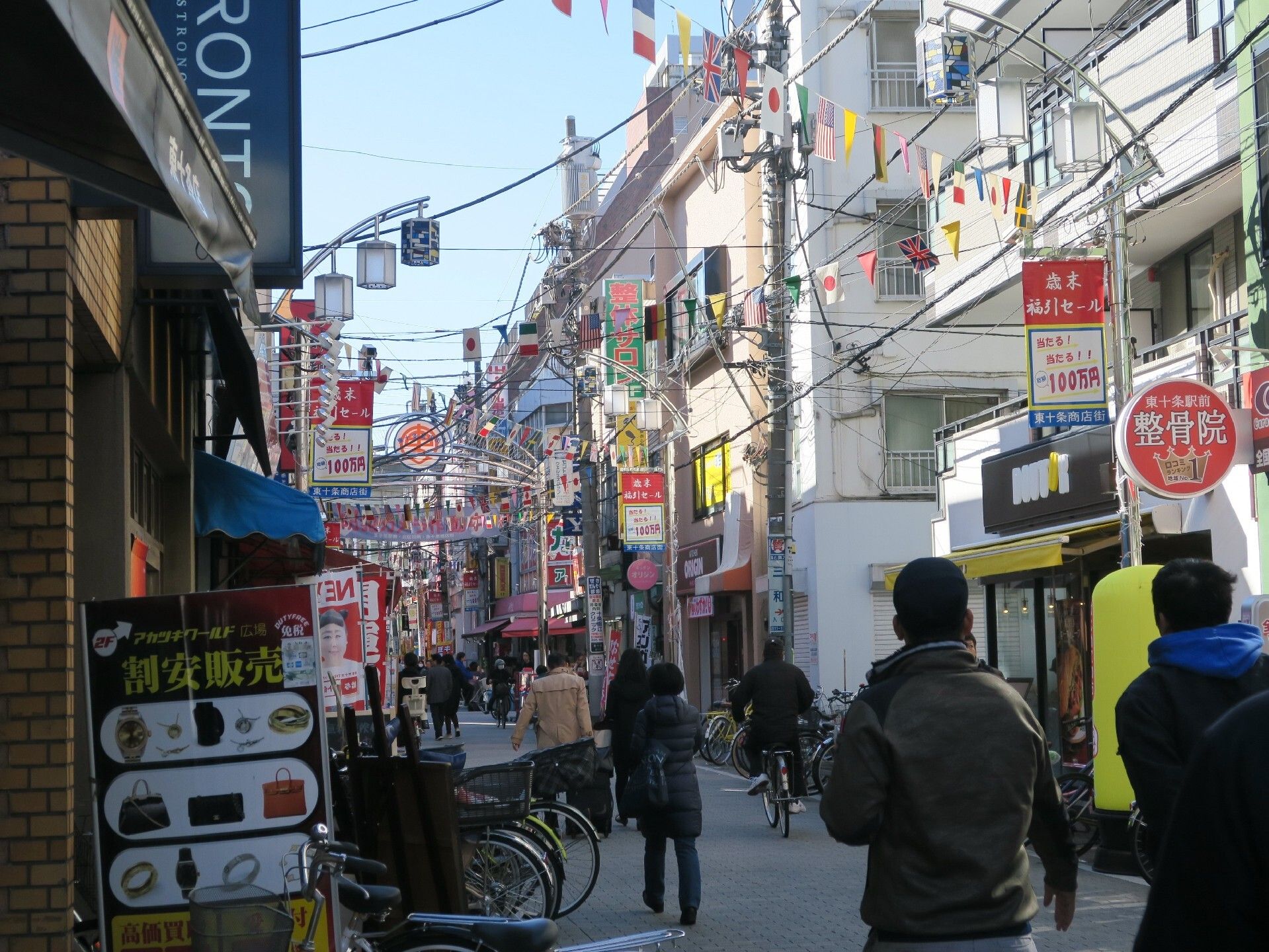 商店街には、整骨院やコーヒーショップなどのさまざまな店舗がひしめいている。多くの人や自転車が行きかい、賑やかである。