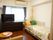 介護ベッドやテーブルなど大きな家具が置かれている。ダークブラウンの洋服ダンスの上には、テレビが設置されている。