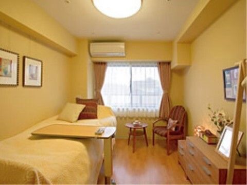 窓際にテーブルとチェアが置かれ、ベッドとチェストが設置された部屋