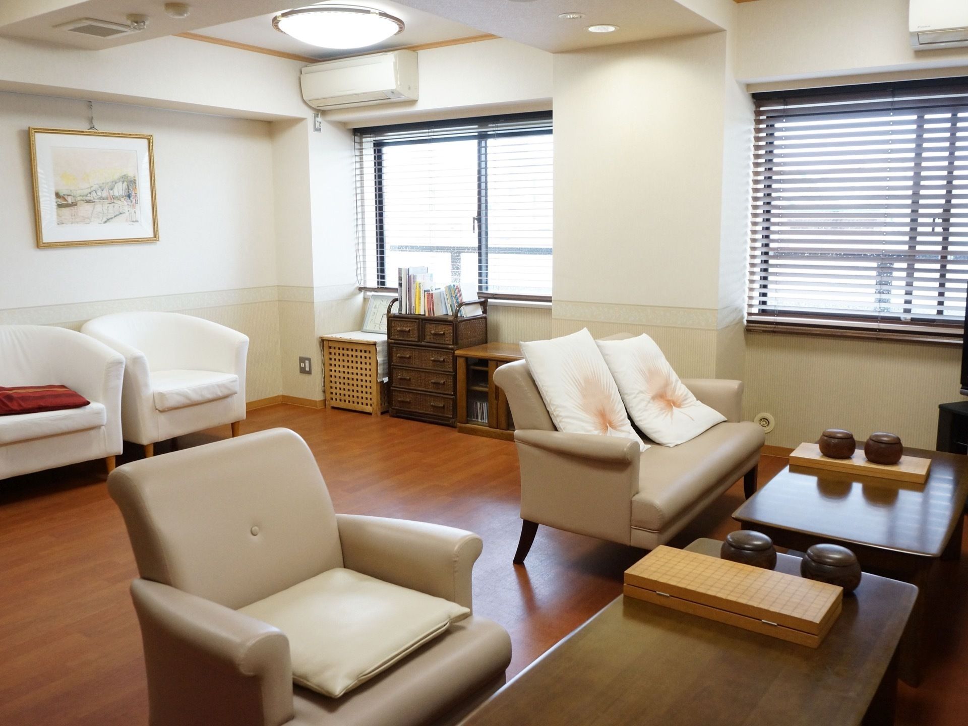 窓にはブラインドカーテンが取り付けられており、壁には木製のフレームに入れられた風景画が飾られている。