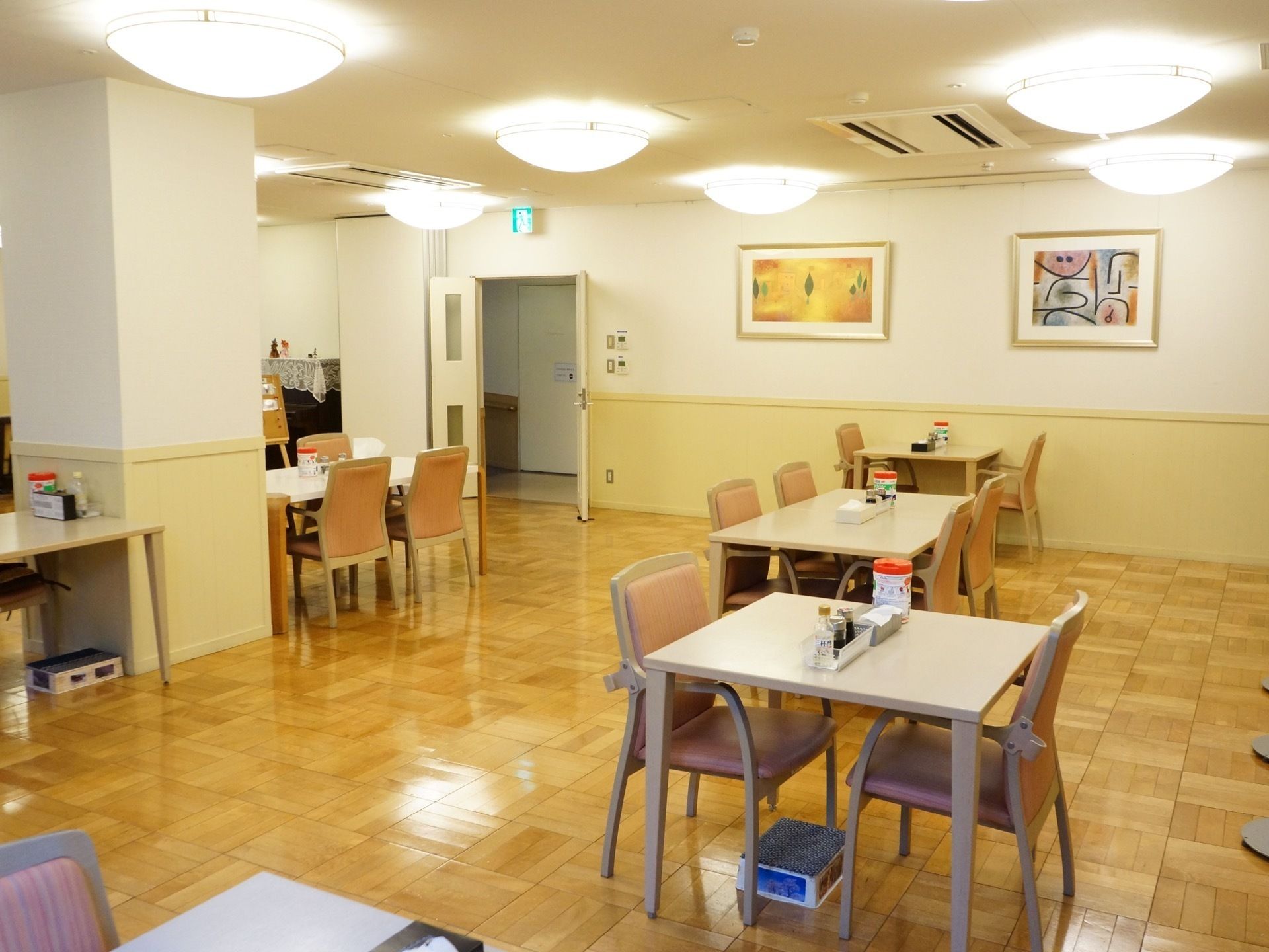 木目調のフローリングの床の上に、ダイニングテーブルとひじ掛け付きの椅子が複数セッティングされている。