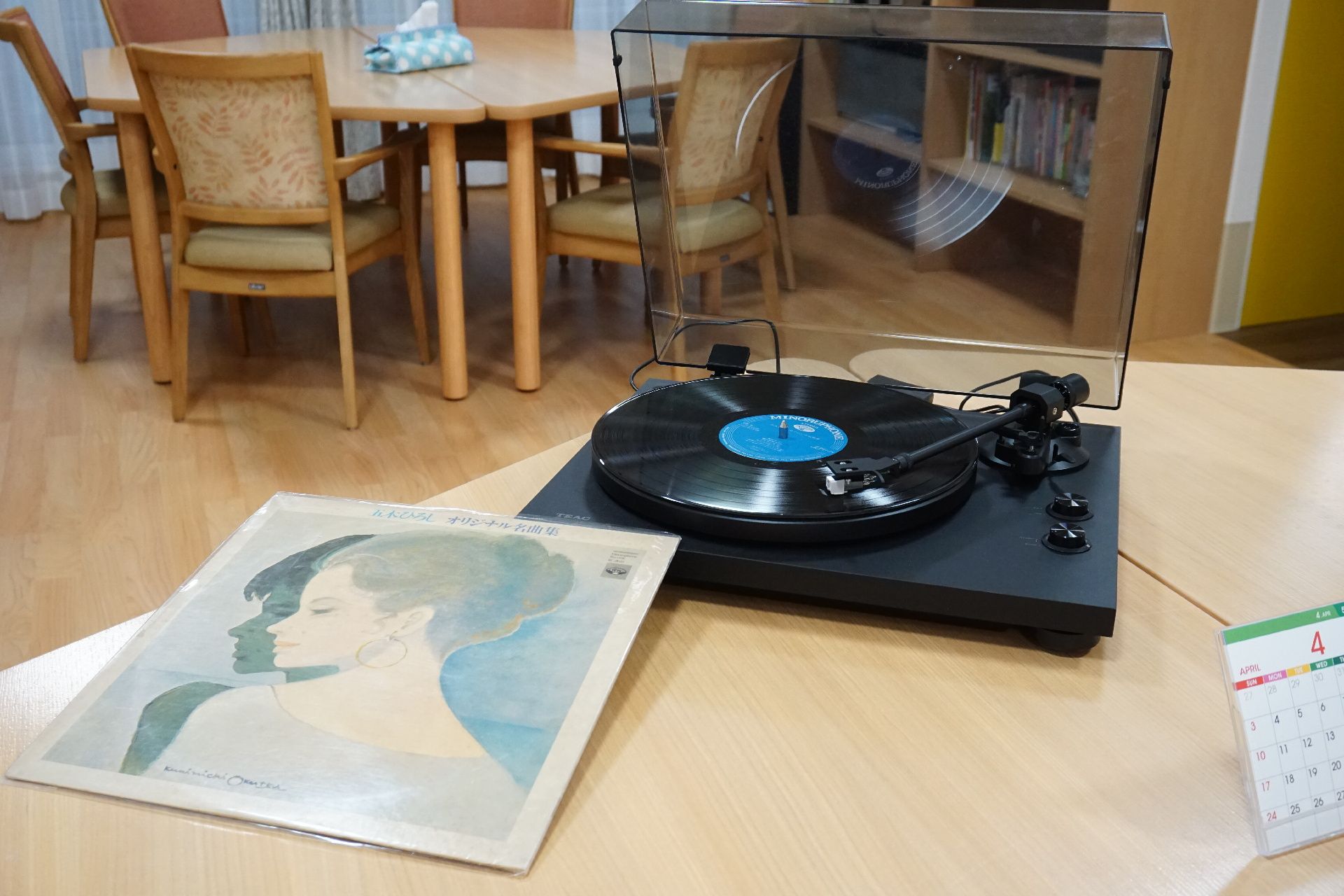 テーブルに置かれたレコードプレイヤーと女性の絵が描かれたレコード