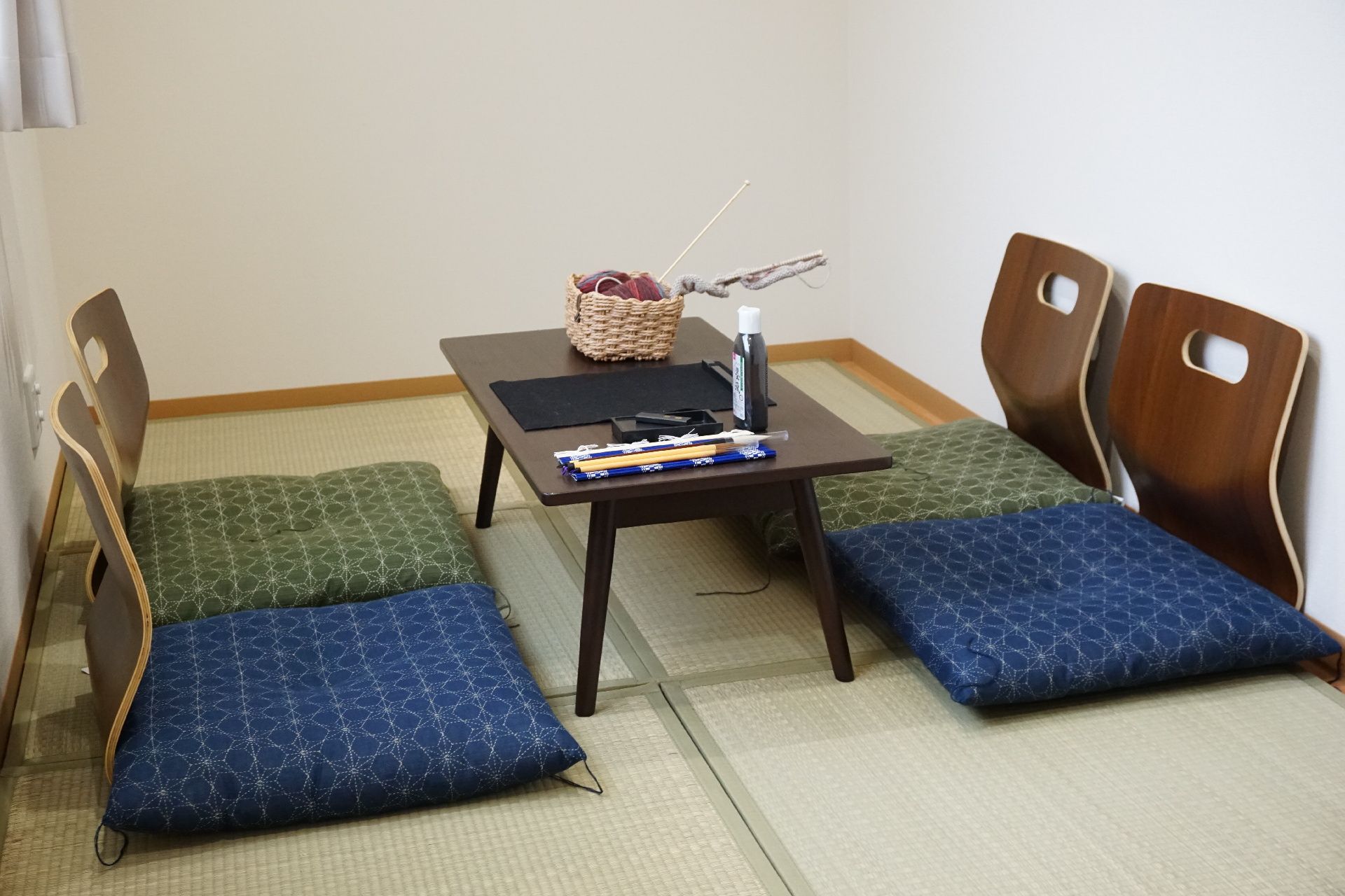 フローリングの部屋には畳風のマットが敷かれ、テーブルや座椅子が置かれている。座椅子には座布団も設置されている。