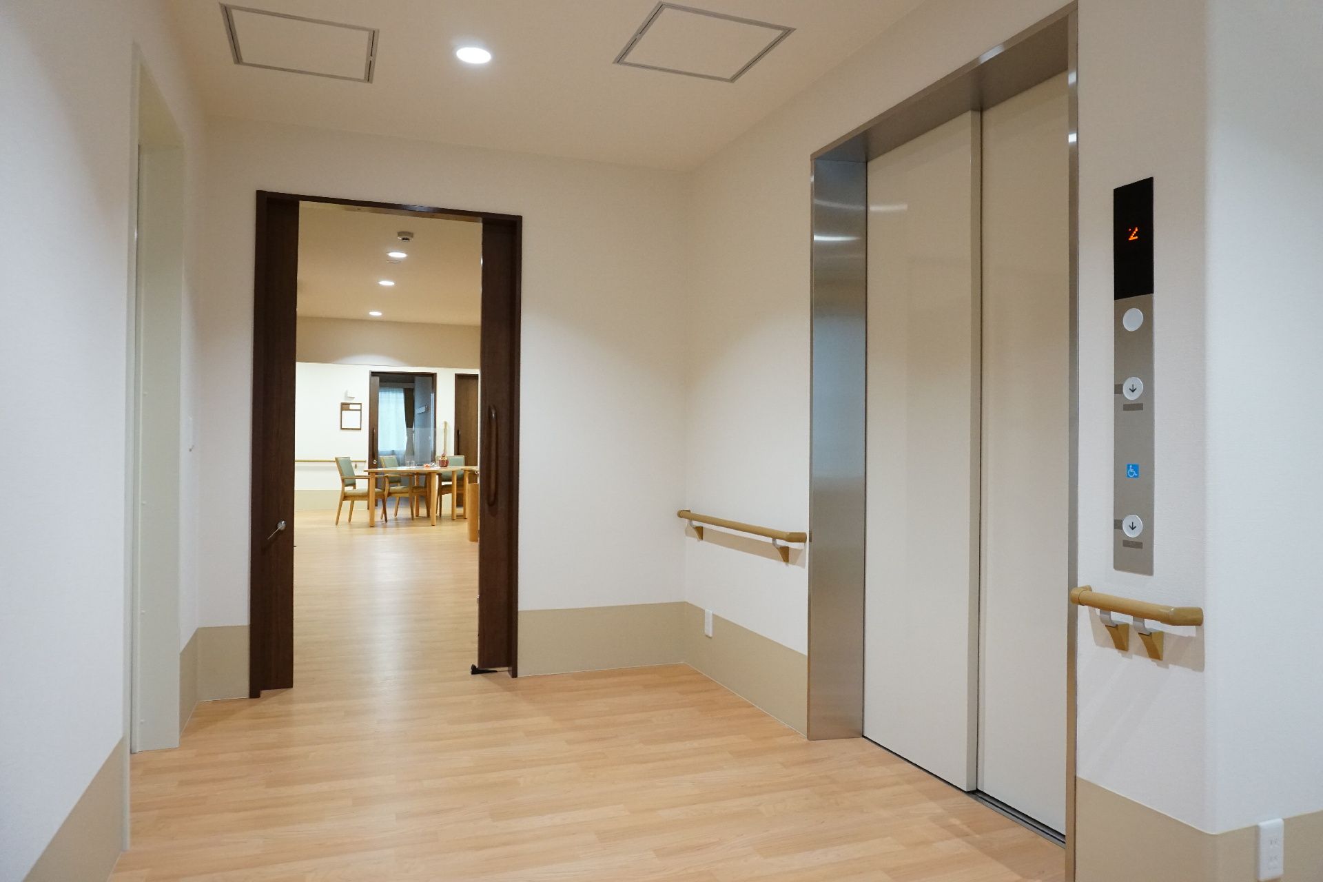 館内の壁には木製の手すりが設置され、エレベーターには白い扉が付いている。扉の右側には操作ボタンがある。