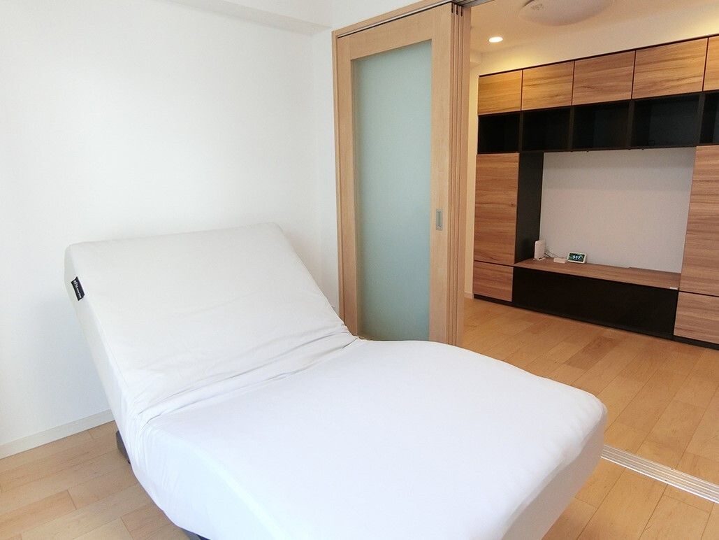 フローリングの部屋は寝室とリビングに分かれ、寝室にはリクライニングベッド、リビングにはテレビボードが設置されている。