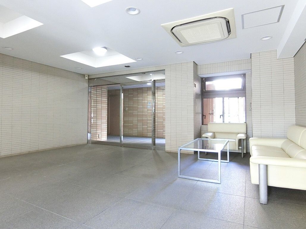 大きな自動ドアが設置されたエントランス。ロビーは広く、白いソファの応接セットが置かれている。