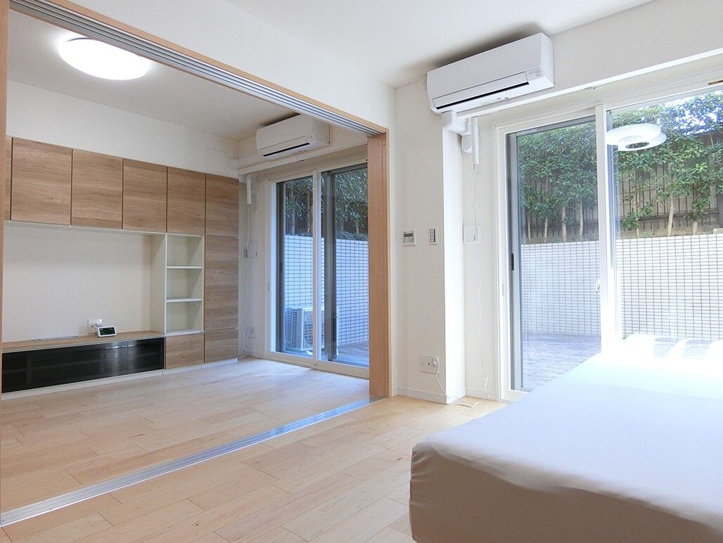 エアコンが設置されたフローリングの部屋が二間続きであり、手前にはリクライニングベッドを置いた寝室、奥にはリビングがある。