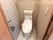 タオル掛けや操作パネル、トイレットペーパーホルダーが壁に設置されたトイレ。フロアは大理石風。