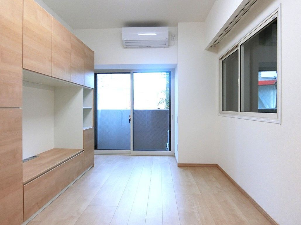 大きな窓が付いたフローリングの部屋にはエアコンが設置され、テレビボードにはたくさんの収納がついている。