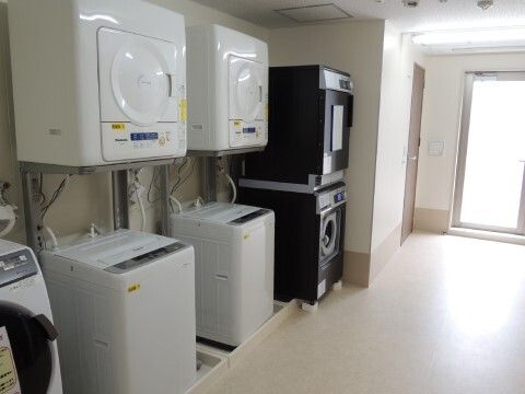 洗濯機の上に乾燥機が設置されている、掃除が行き届いていてきれいな洗濯室