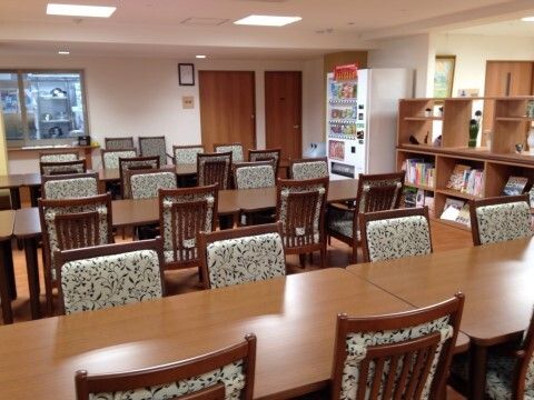 テーブルと椅子が整然と並べられ、壁際に飲料の自動販売機が設置されている食堂