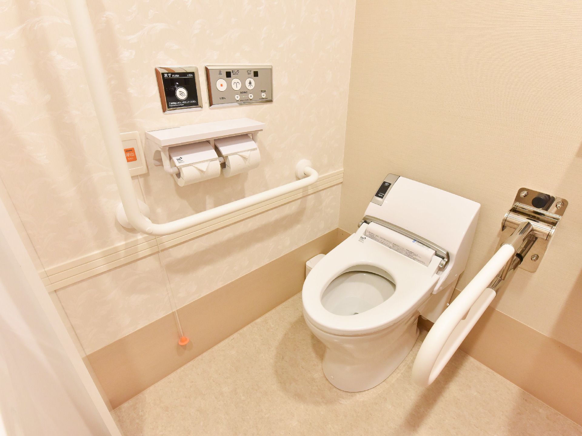 便器は水洗の全自動。横には可動式の手すり。壁にも手すりとトイレのスイッチ。呼出ボタンにインターホンも設置されている。