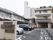 左手前に施設名の看板がある。駐車場には自動車が数台駐車してある。地面に白く「消防活動空地」の文字がある。