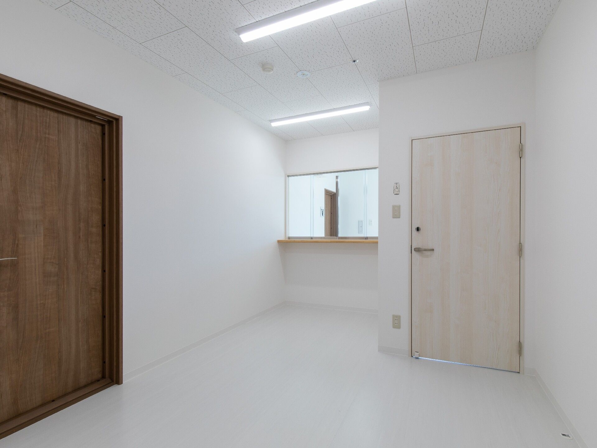受付のようなカウンターがある部屋には家具は置かれていない。右側と左側にそれぞれドアが付いている。