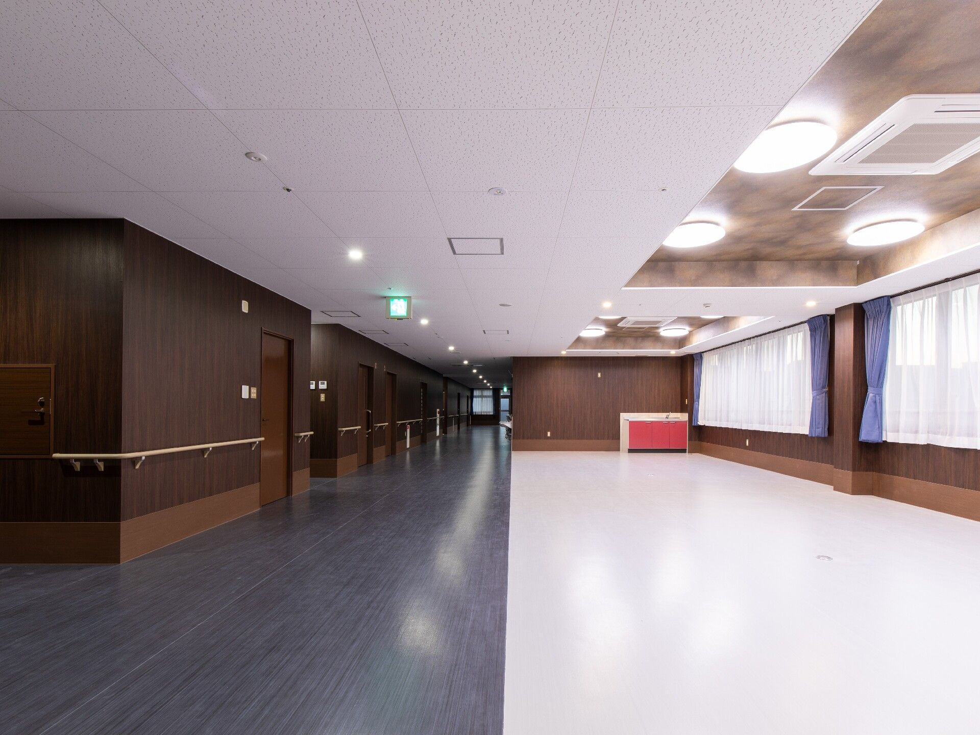 手すりが付いたまっすぐなろうが左側にあり、右側には家具などは置かれていない共有スペースがある。