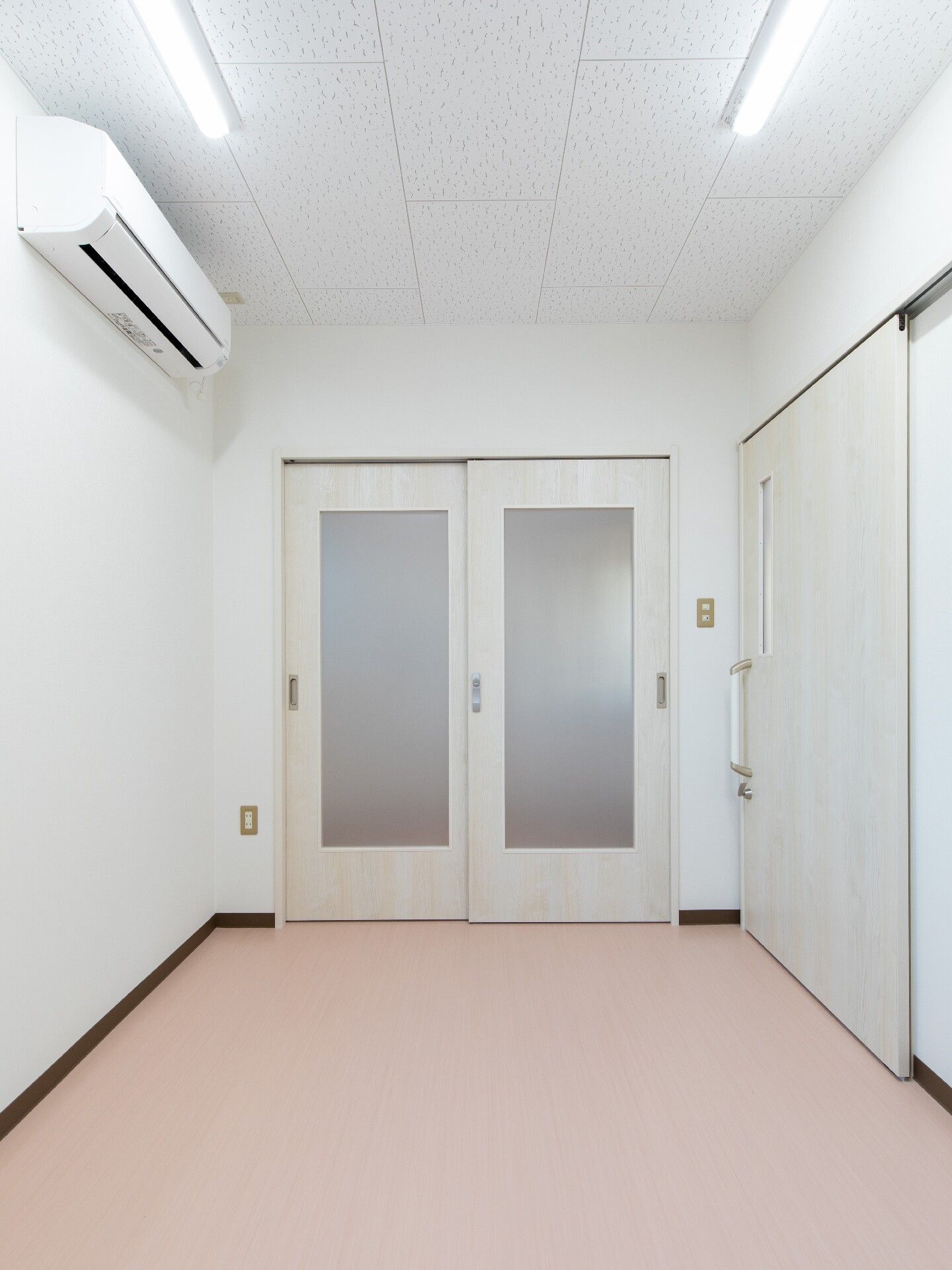 エアコンが付いた部屋には白いドアがあり、収納スペースも付いている。家具は置かれていない。