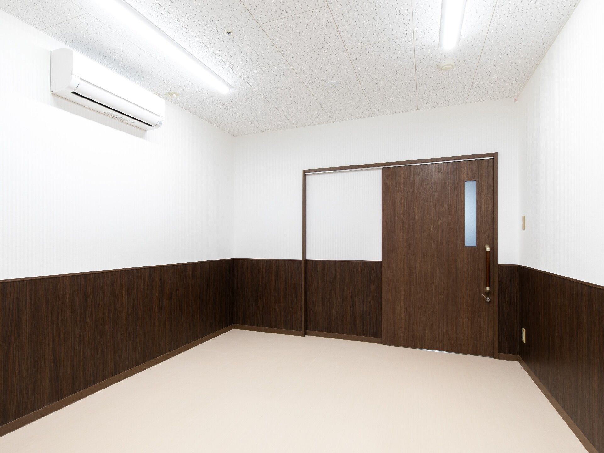 ブラウンのスライド式のドアが設置された部屋の中には家具は置かれていない。エアコンが付いている。