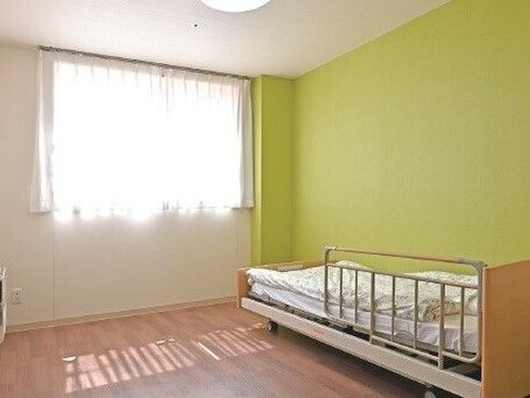 カメラに向かって笑顔を見せるスタッフと高齢者の女性。施設での何気ない一場面の様子