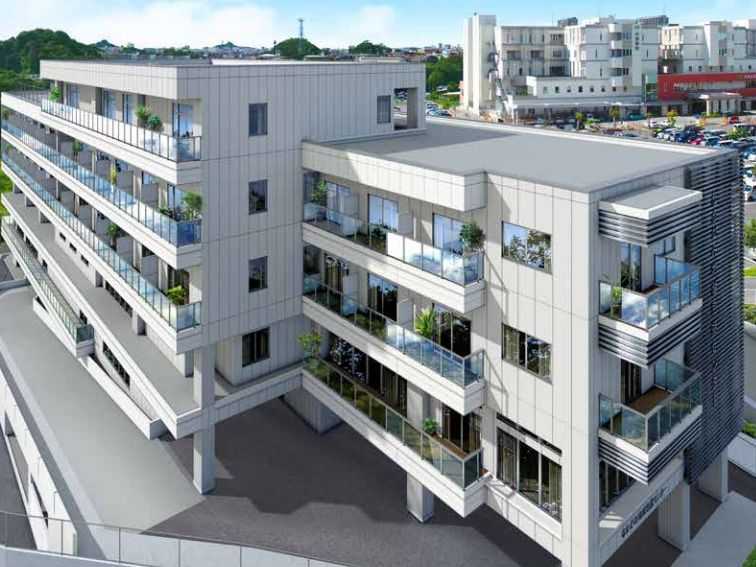 白を基調とした大きな建物。各フロアにベランダがあり、周辺には緑も多く、遠方には白い大きな建物がある。