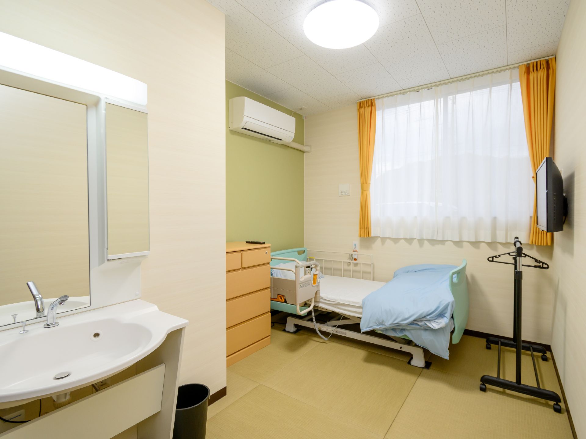 窓から日差しが差し込み、介護ベッドが置かれている居室