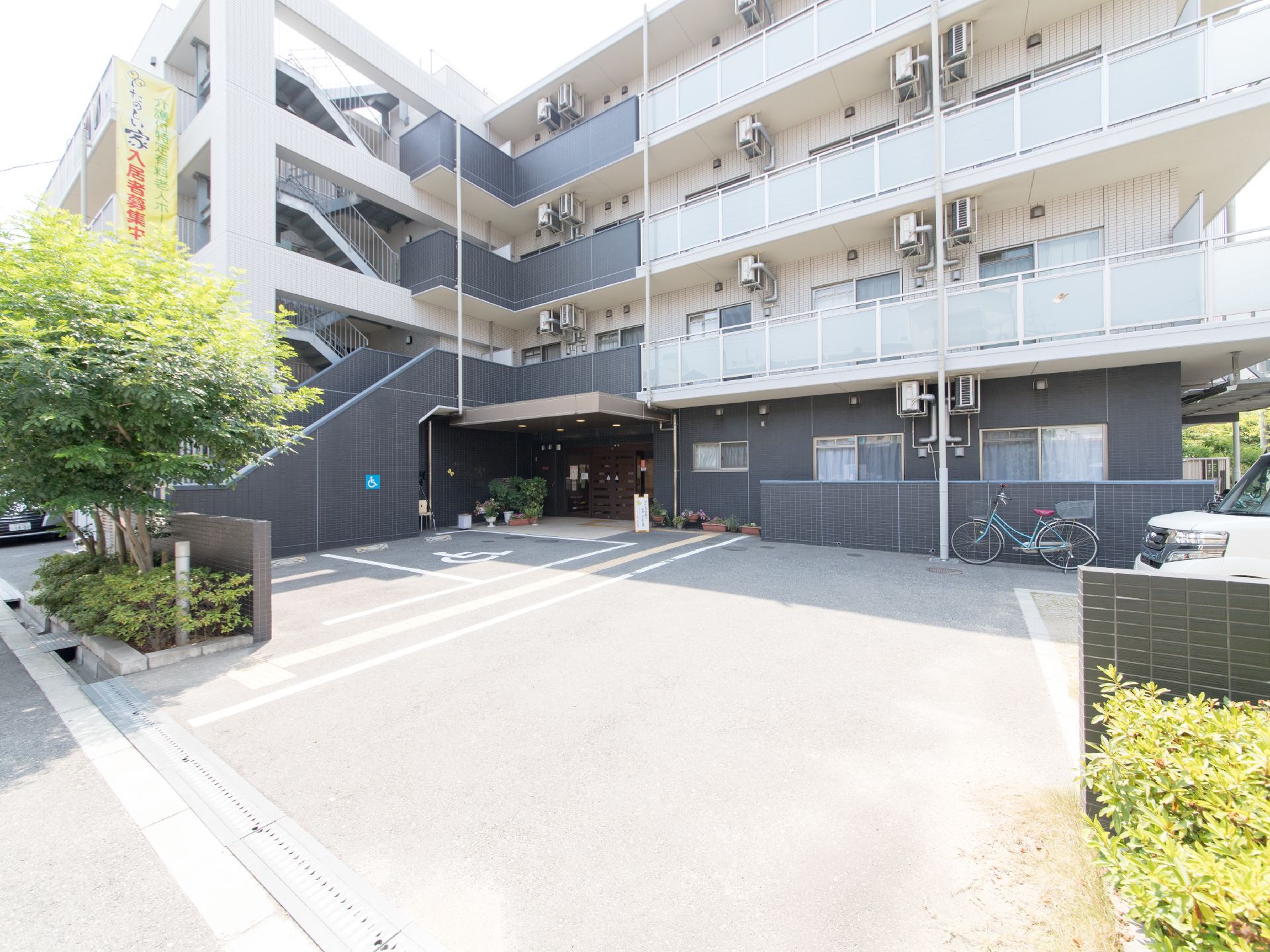 建物は、4階建ての鉄筋コンクリート造り。黒と白のツートンカラーの建物に、黄色い入居者募集用の垂れ幕が掛かっている。