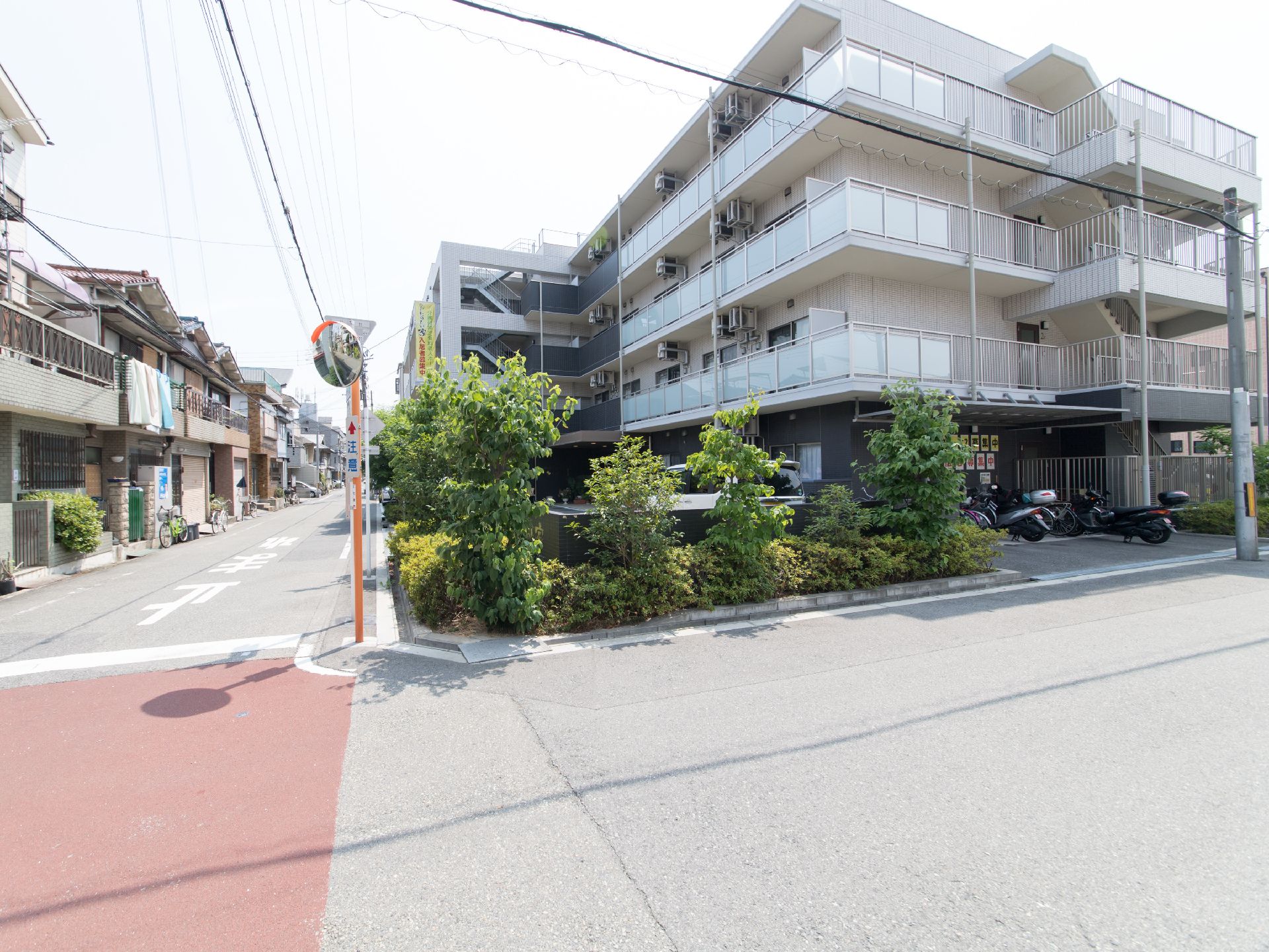 施設は、角に建てられている。道路を挟んで向かいには、一戸建てが並んでいる。施設の周りには植栽がある。