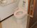 便座にピンクのシートが貼られたトイレは広く、出入り口にスライド式のドアが付いている。