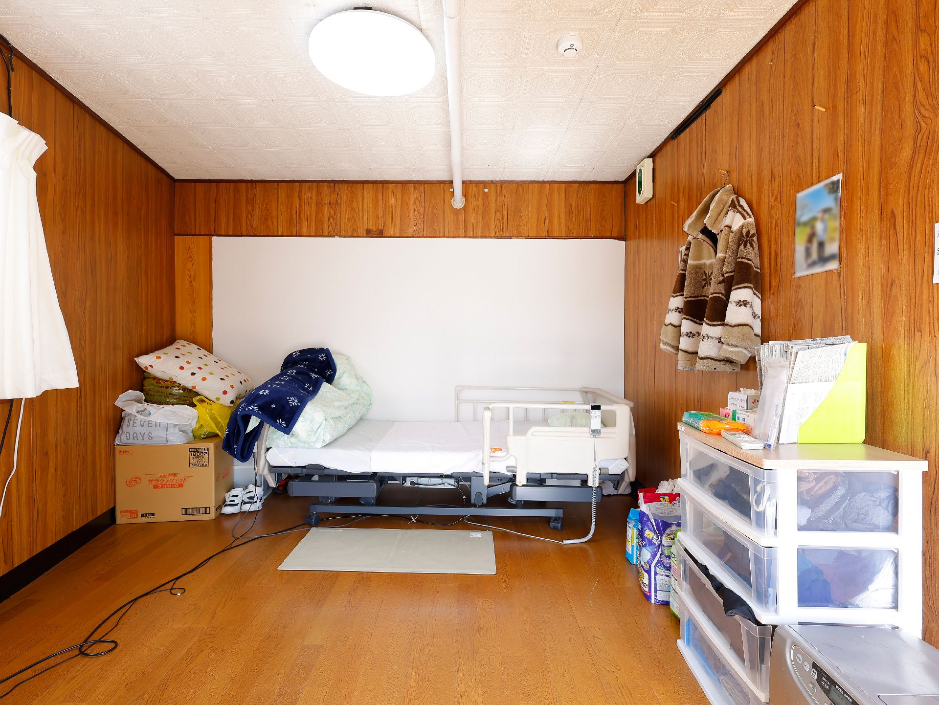 カルテのようなものを見ながら話しているブルーのエプロンを付けた若い女性スタッフと高齢女性、
