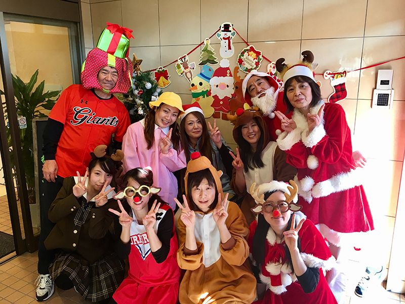 エントランスの近くでスタッフが集合してカメラの方を向いている。サンタクロースやトナカイ、幼稚園児の仮装をしている。