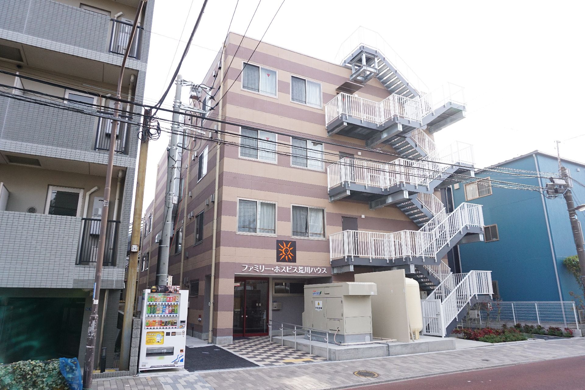 水の入ったコップを持った女性スタッフが笑顔で高齢女性が薬を飲み終えるのを待っている。