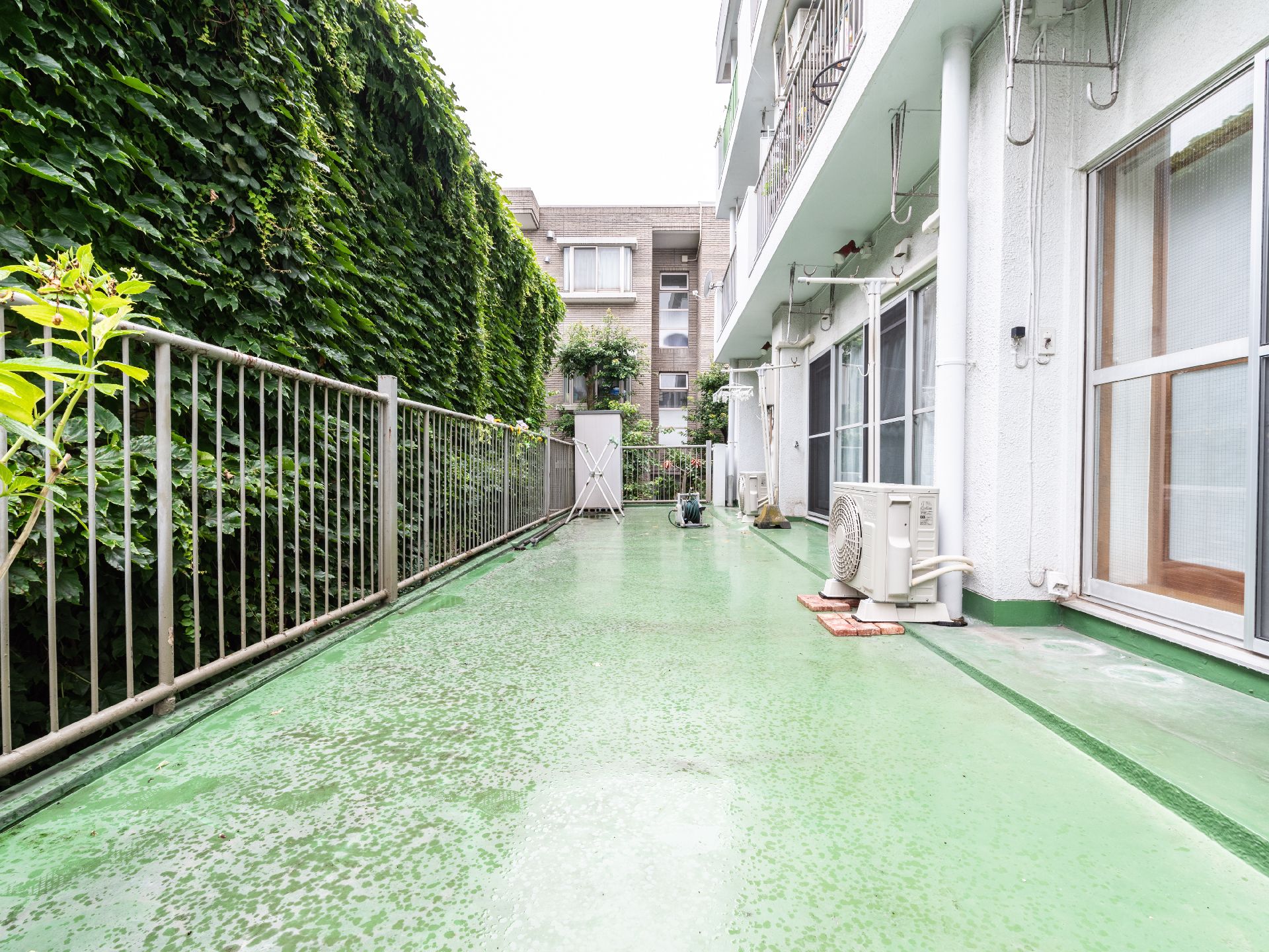 フェンスの先に植物が生い茂っているバルコニー