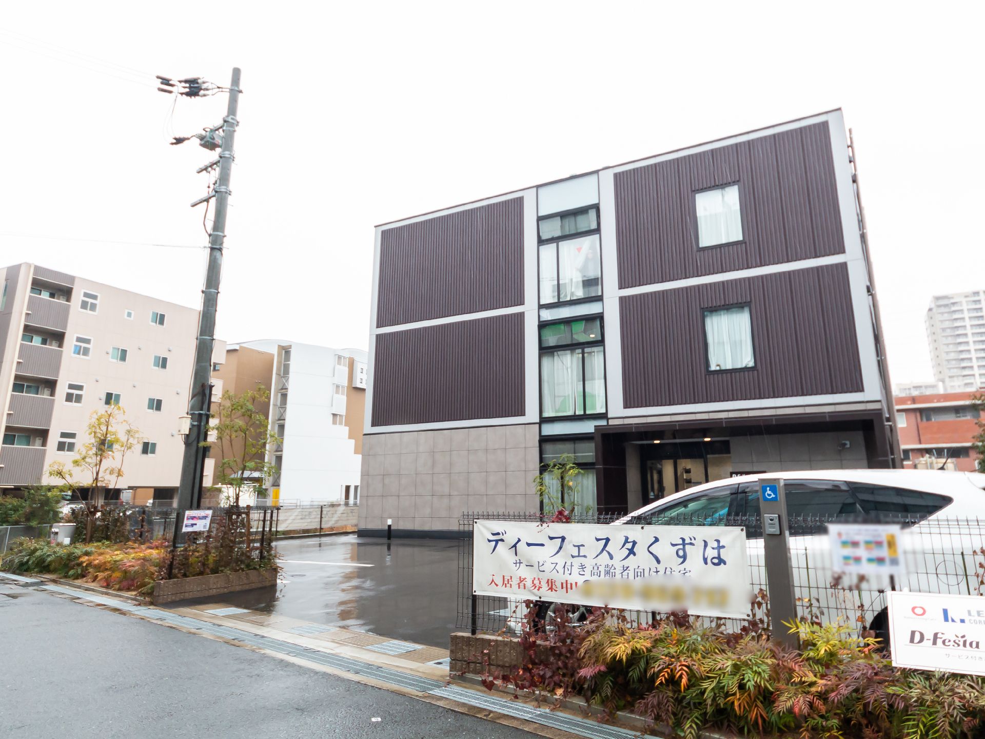 茶色とグレーをベースとした、駐車場もある介護施設の外観