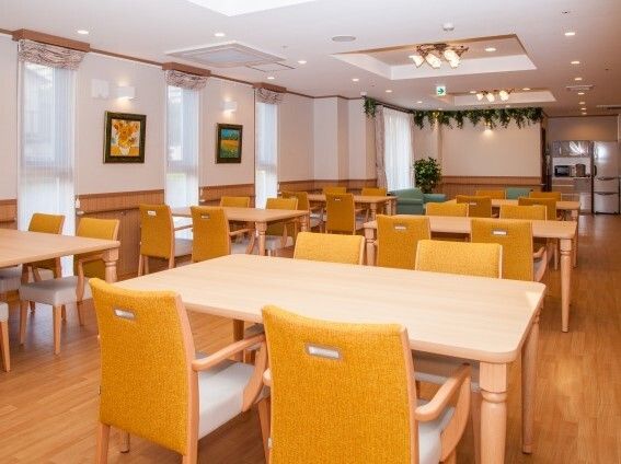 4人掛けの木製のダイニングテーブルセットが置かれた食堂にはたくさんの窓があり、壁には複数の絵画がある。