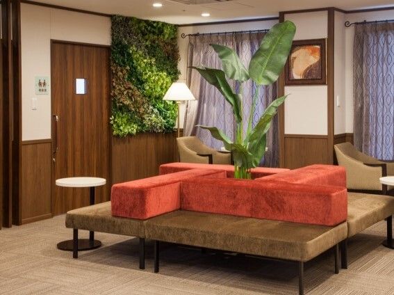 観葉植物が飾られたロビーには赤とブラウンの四角いソファのような椅子が置かれ、小さなテーブルもある。