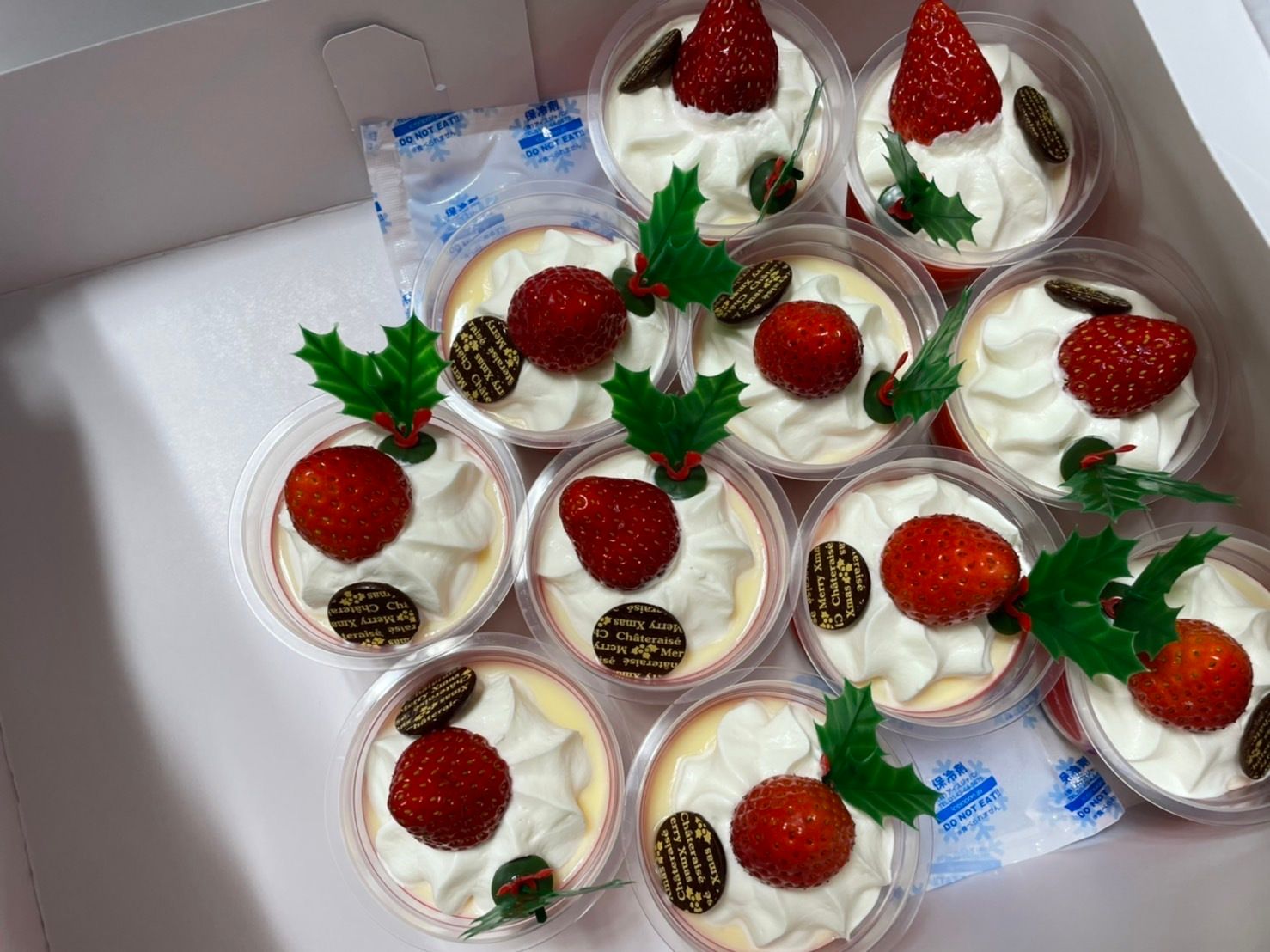 いちごやホイップクリーム、チョコレートや柊の葉が乗ったプリンがたくさん置かれている。