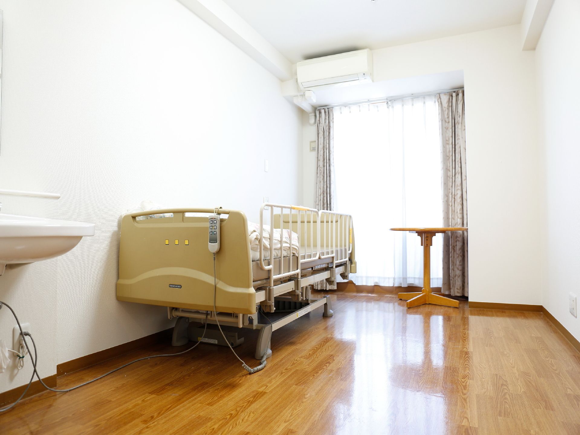 介護ベッドが設置された、白を基調としたシンプルな居室内