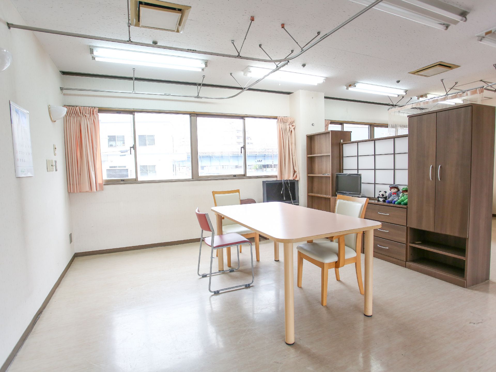 なにかを見ながら談笑しているスタッフと高齢者の様子。施設内の会話の場面